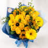 Yellow roses and gerbera daisies in blue wrapping with ribbon