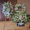 White floral funeral wreaths on stands with roses and lilies