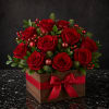 Red roses arranged in a wooden box with a red ribbon bow