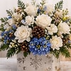 Creamy white roses and blue hydrangeas are arranged with delicate white accents