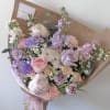 Pastel bouquet of roses, peonies, and lavender flowers wrapped in brown paper