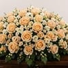 A full and elegant casket spray featuring peach roses, coordinating seasonal blooms