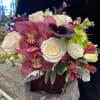 Bouquet of white roses, pink orchids, and dark calla lilies in a vase