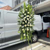 Tall standing floral spray with white roses and greenery on a metal easel