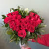 Handheld bouquet of red roses with green foliage