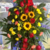 Standing floral spray with red roses, sunflowers, and purple flowers