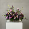 Mixed purple and pink flower arrangement in a wooden box