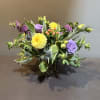 Mixed bouquet in a square glass vase with yellow, purple, and pink blooms