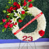 White floral funeral wreath with red roses and lilies on a stand