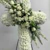 White floral cross on a stand with roses and chrysanthemums