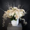 Cream floral arrangement in a white vase with curly decorative accents