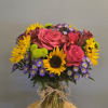 Bouquet of pink roses, sunflowers, and purple daisies in a glass vase