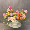 Mixed bouquet of pink, yellow, orange, and lavender roses in a white vase