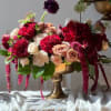 Arrangement of red, blush, and white roses in a gold vase