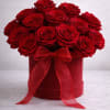 Red roses arranged in a round hatbox with a red ribbon bow