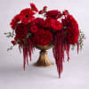Red roses and gerbera daisies arranged in a gold pedestal vase