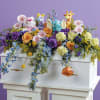 Colorful floral arrangement with plush animals on a white casket