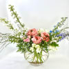 Mixed floral arrangement in a round glass vase with pink and white blooms