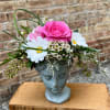 Pink rose arrangement in a blue face-shaped vase with white daisies