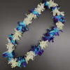 Flower lei with white, blue, and purple blossoms on a dark background
