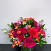 Mixed bouquet of pink, orange, and red flowers in a glass vase