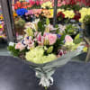 Bouquet of pink roses, lilies, and pale hydrangeas wrapped in gray paper