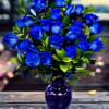 Blue roses arranged in a purple glass vase