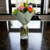 Bouquet of pink, yellow, and orange roses in a glass vase