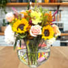 Mixed bouquet with sunflowers, roses, and hydrangeas in a glass vase