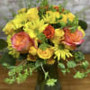 Bouquet of yellow daisies and orange-pink roses in a dark vase