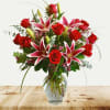 Red roses and pink lilies in a clear glass vase