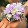 Wrist corsage with lavender and white roses on a hand