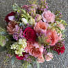 A lush, rounded flower arrangement that reads as both romantic and cheerfully