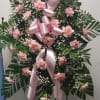 Pink carnation standing spray with a large pink ribbon on an easel