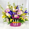 Mixed bouquet in a pink container with small garden tools