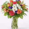 Mixed bouquet of orange, pink, and white flowers in a clear glass vase