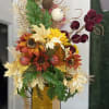 Tall autumn floral arrangement in an amber glass vase