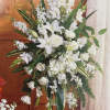 Tall white floral standing spray with lilies and roses on a metal easel