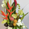 Tropical arrangement with red heliconia, white orchids, and green anthuriums in a white vase