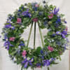 Select this 22" sympathy wreath that includes iris, blue thistle, and carnations.