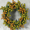 Round wreath of orange and green berries on a gray background