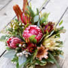 Bouquet of pink protea and mixed greenery on a wooden surface