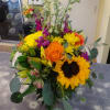 Mixed bouquet with sunflowers, orange roses, and purple blooms