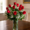 Red roses arranged in a clear glass vase with white filler flowers