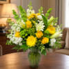 Sunlit yellow roses and cheerful gerbera-like daisies meet crisp white lilies in