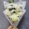 White bouquet with daisies, roses, and a lily wrapped in patterned paper