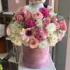 Pink flower bouquet with a plush cow topper in a pink hatbox
