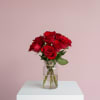 Red roses in a clear glass jar vase on a white pedestal