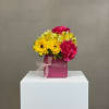 Pink and yellow flowers arranged in a magenta box with a ribbon