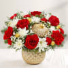 Red roses and white daisies in a gold vase with holiday ornaments